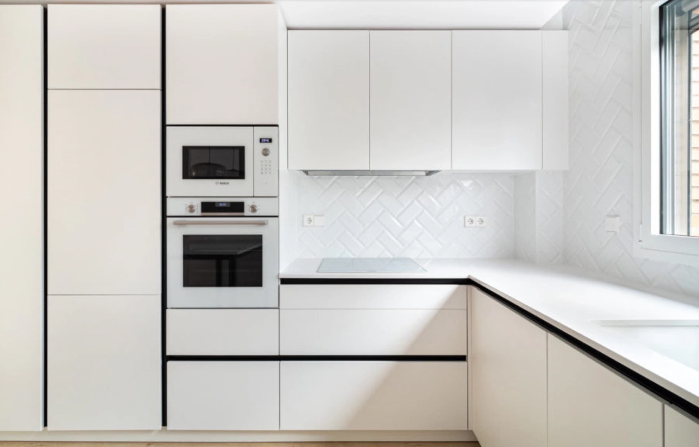 Cocina blanca con encimera clara en L y placa de cocción