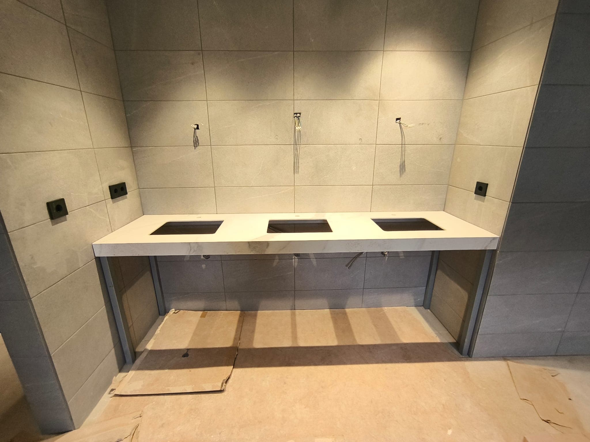 Encimera de baño clara con huecos preparados para tres lavabos